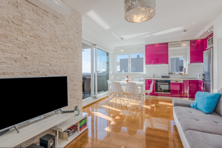 Vardagsrum med utsikt över det rosa köket.