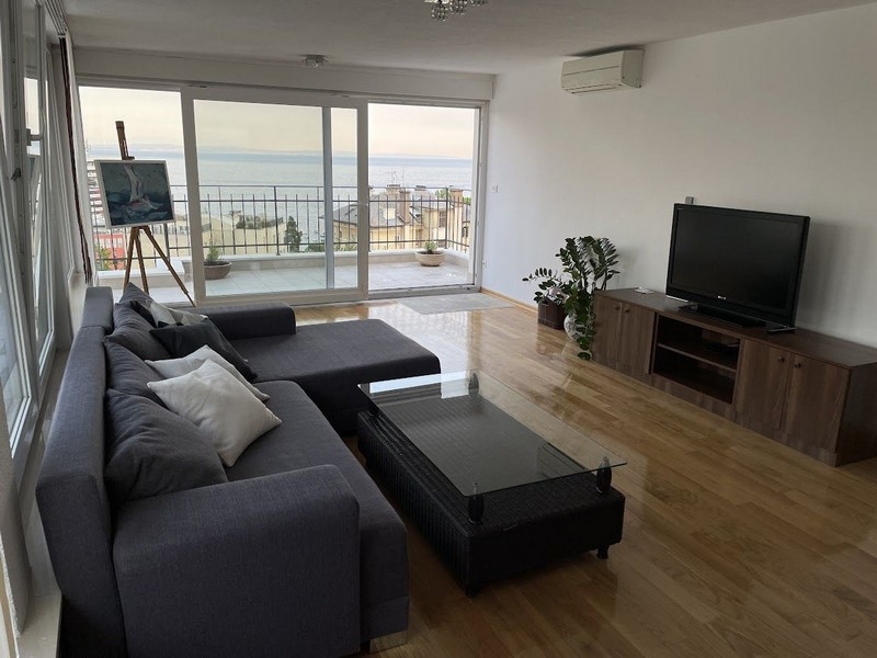 Vardagsrum med utsikt över terrassen och havet.