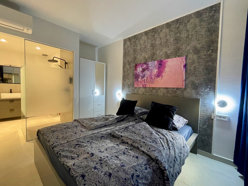 Interiörvy av ett badrum med duschskärm i glas och utsikt över ett ljust rum i en lägenhet till salu i Zadar, Kroatien