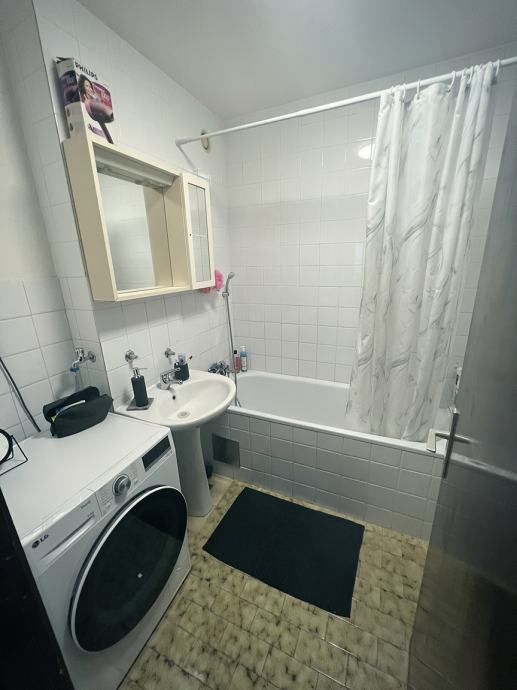 Badrum med tvättmaskin och badkar.