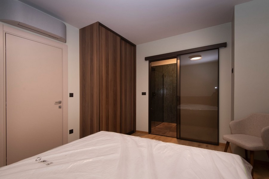 Sovrum med direkt tillgång till badrummet i en modern lägenhet till salu i Split, Kroatien, med stor säng och elegant inredning.