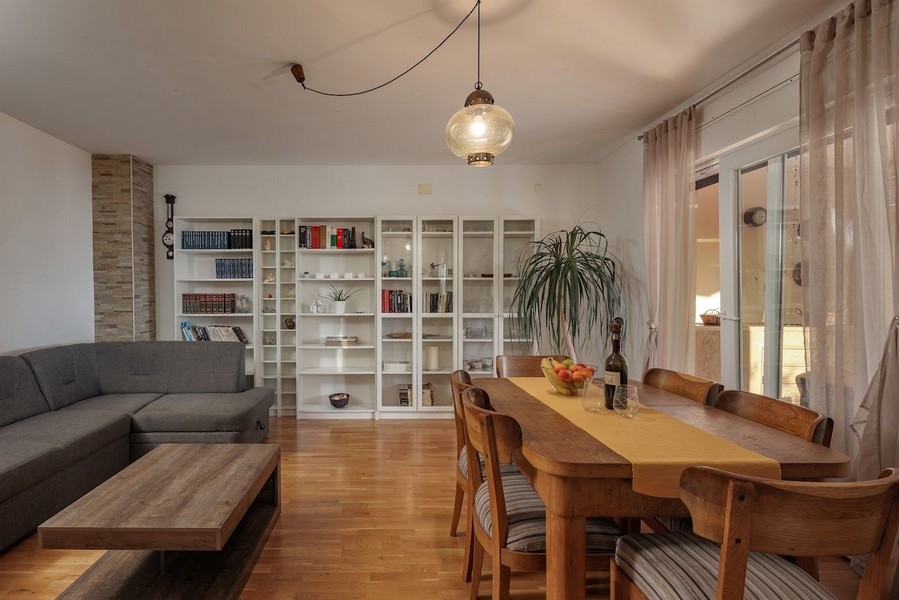 Vardagsrum och matplats med bokhylla och stort bord i kroatisk egendom.