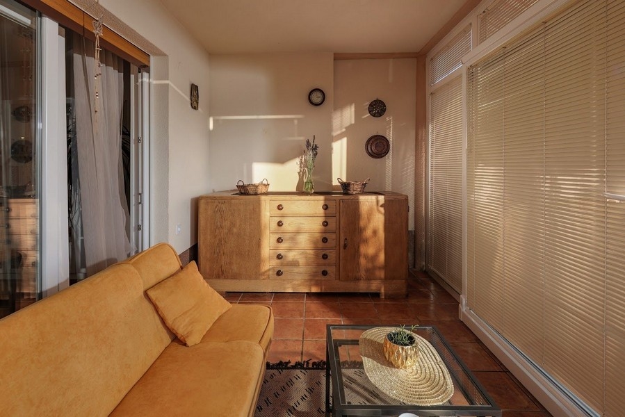 Soldränkt vinterträdgård i en kroatisk lägenhet med en gul soffa.