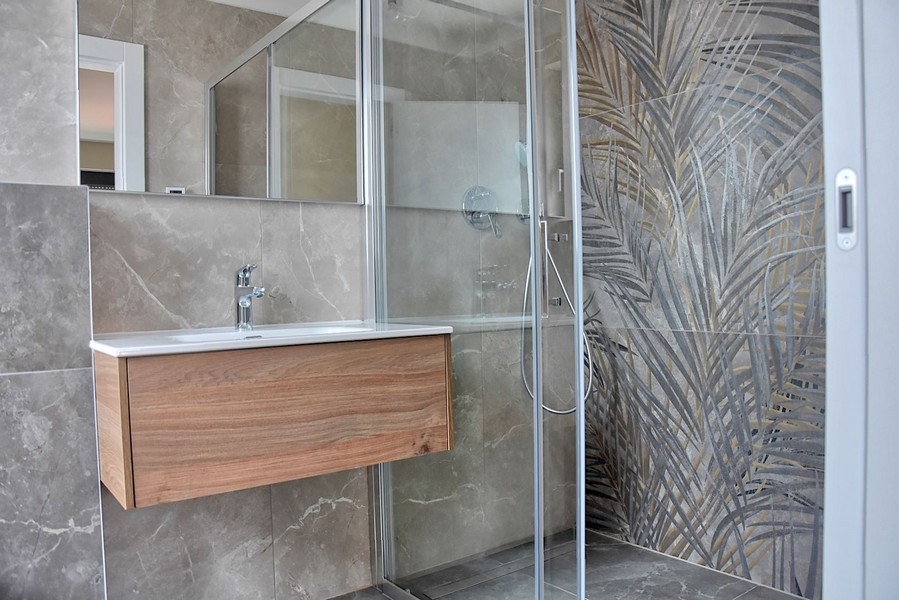 Modernt badrum i en takvåning i Istrien med duschkabin med dekorativa glasplattor och en underdel i trä.