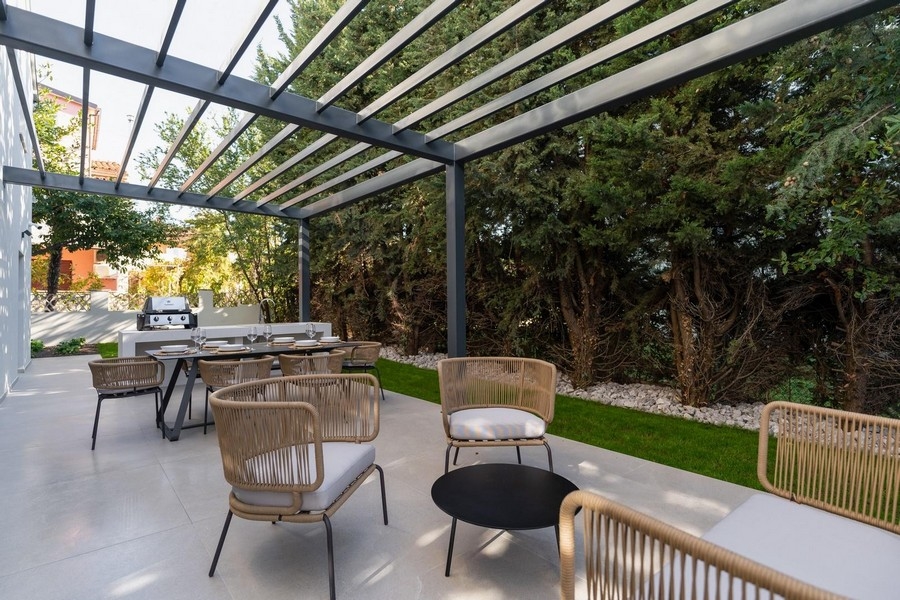 Exteriör vy av terrass med sommarkök och matplats i Istriens lyxlägenhet omgiven av grönska