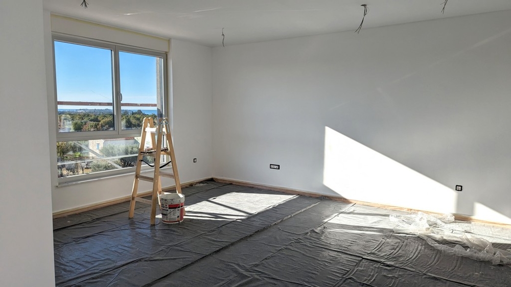 Ljust rum under renovering med stege och målningsmaterial, en del av en lyxig fastighet i Istrien.