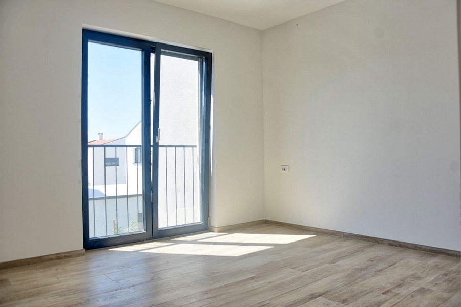 Ljust sovrum med balkongdörrar och laminatgolv, en del av ett fastighetserbjudande i Porec