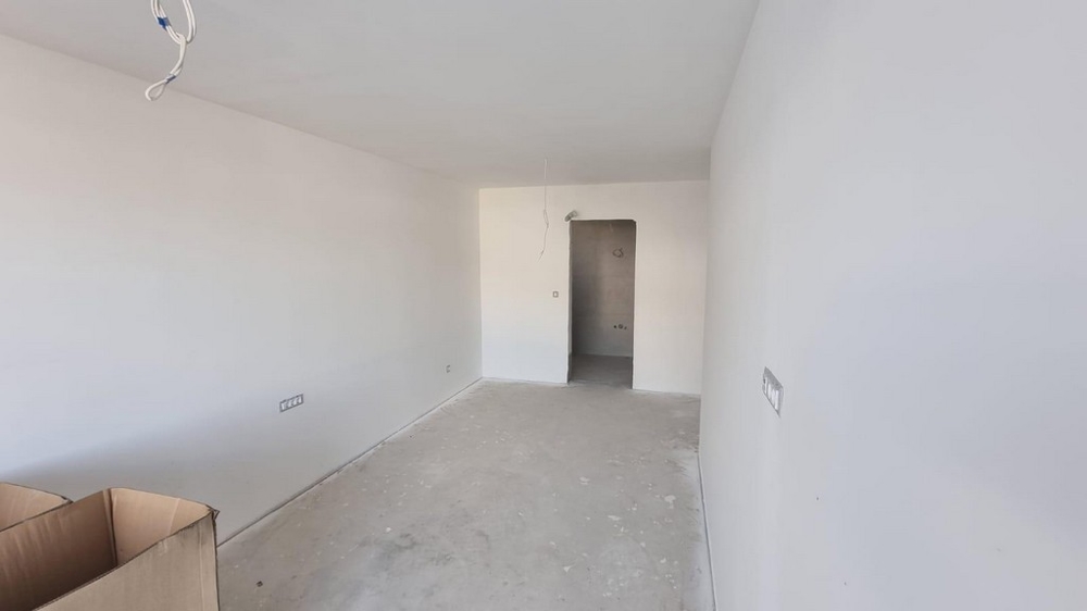 Tomt rum i en lägenhet i Kroatien med ljusa väggar och betonggolv.