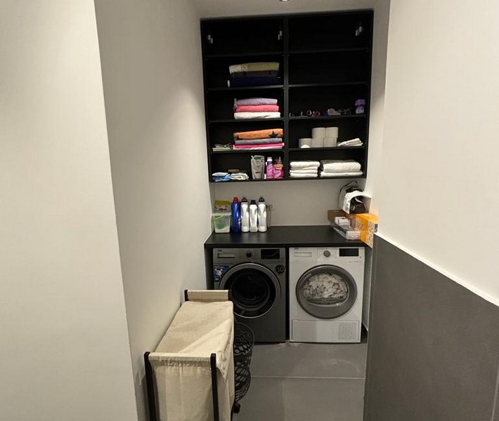 Tvättstuga med tvättmaskin och inbyggt skåp för handdukar, del av en lägenhet till salu i Rijeka, Kroatien.