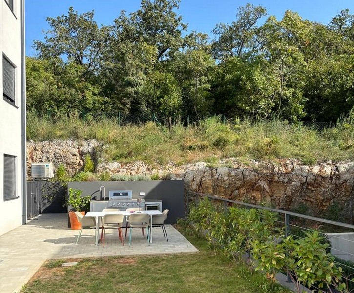 Trädgårdsområde med utomhuskök och sittplatser, del av en lägenhet till salu i Rijeka, Kroatien.