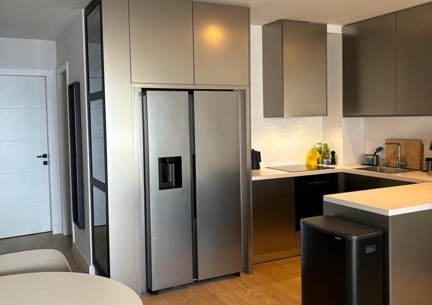 Modernt kök med rostfritt kylskåp och mörka skåp, en del av en fastighet i Rijeka, Kroatien.