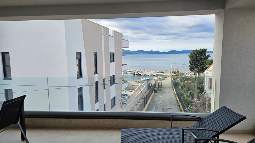 Matplats med bord och stolar i en takvåning till salu i Zadar, Kroatien, med fönsterutsikt över havet