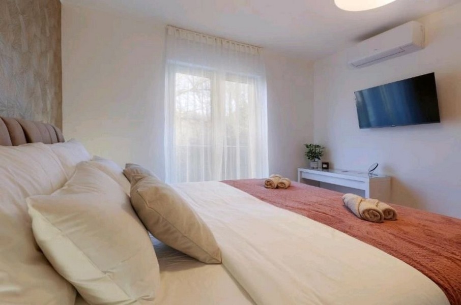 Sovrum med stor säng och TV i lägenhet, till salu nära Opatija, Kroatien