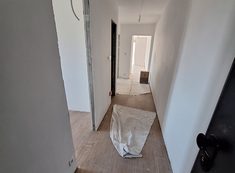 Hall i ny lägenhet, skyddskåpa på golvet, byggnadens skal, ljusa väggar, trägolv, dörrar och rum i bakgrunden, erbjudande från Panorama Scouting i Kroatien.