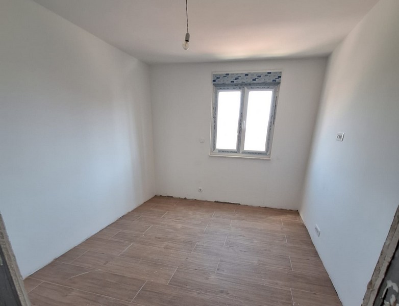 Tomt rum i skalet på en ny lägenhet med trägolv och fönsterfront, vita väggar, takljusanslutning, Panorama Scouting-fastighet i Kroatien.