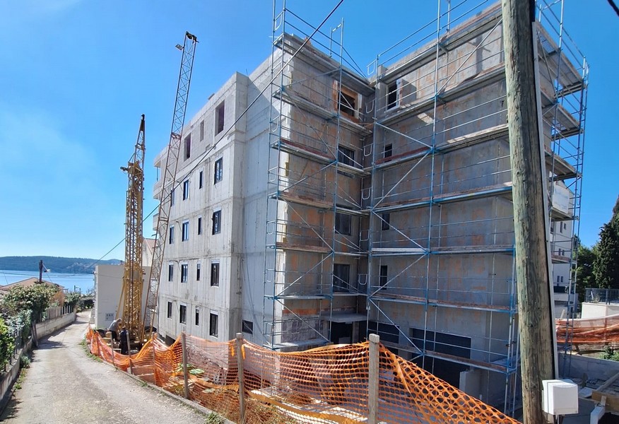 Bakifrån av ett hyreshus under uppbyggnad med ställningar och kran i Kroatien, som erbjuds av Panorama Scouting