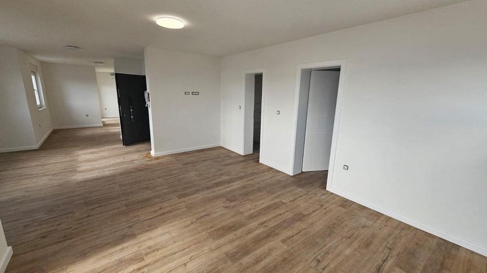 Rymligt vardagsrum i en till salu lägenhet i Crikvenica, Kroatien, med trägolv och vita väggar