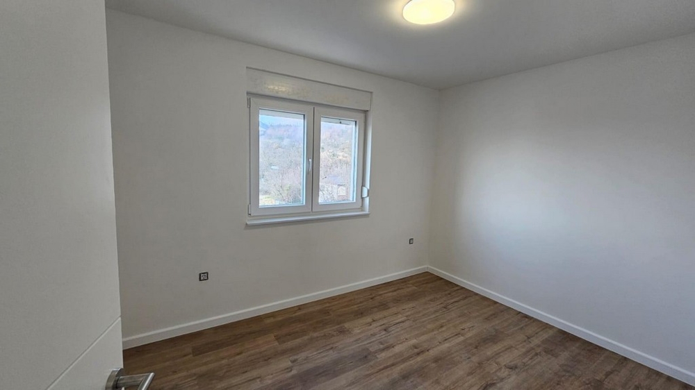 Tomt sovrum i försäljningslägenheten i Crikvenica, Kvarnerbukten, med trägolv och vita väggar