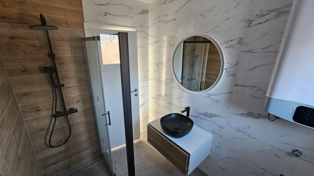 Modernt badrum i en lägenhet till salu i Crikvenica, Kroatien, med marmorplattor, duschkabin och snyggt handfat