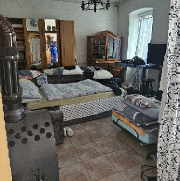 Vardagsrum med flera soffor och vedspis, spegel och tv