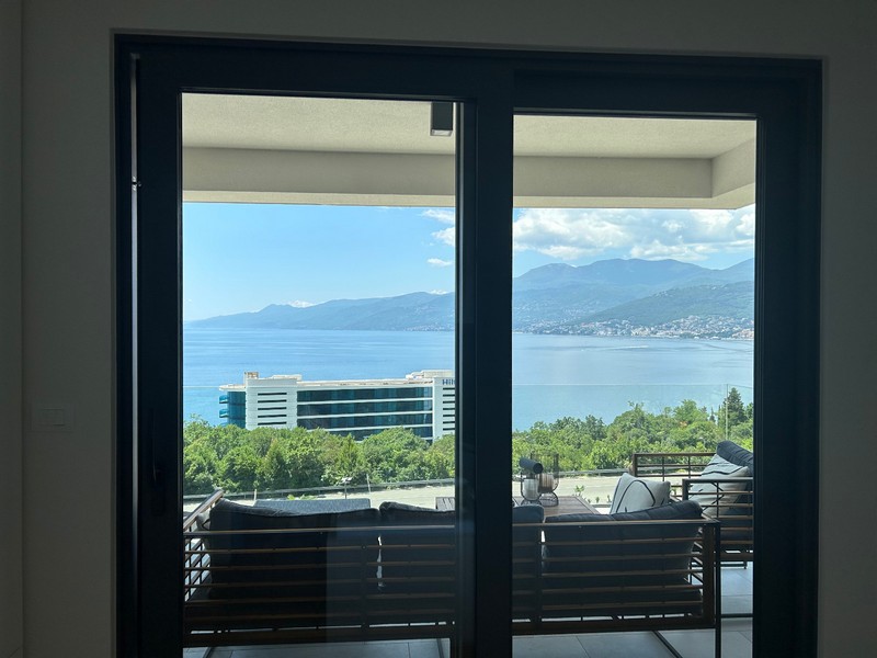 Utsikt genom den öppna altandörren till en modern lägenhet med utsikt över Kvarnerbukten.