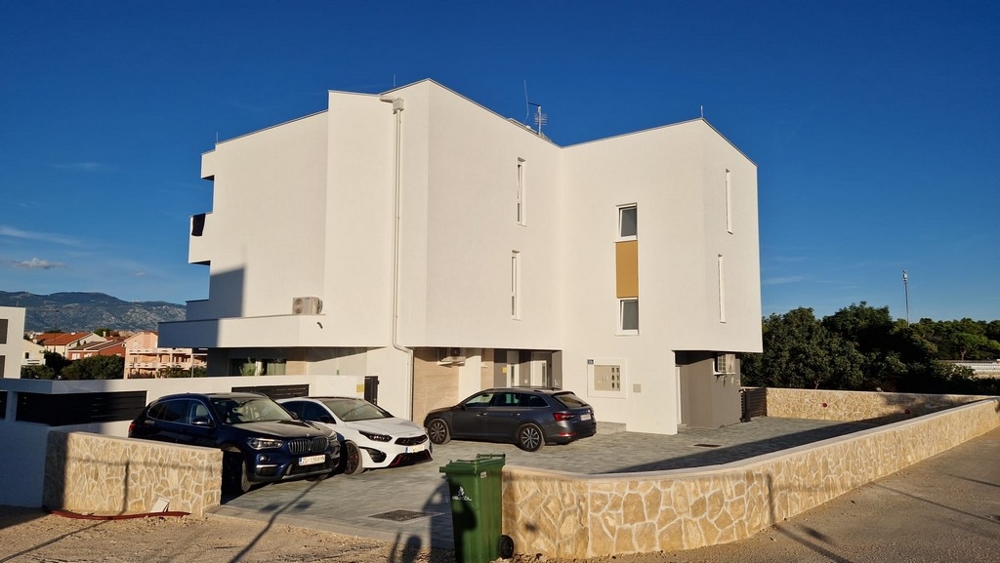 Sidovy av ett modernt flerfamiljshus med parkeringsplatser i Novalja, Pag Island, Real Estate Kroatien