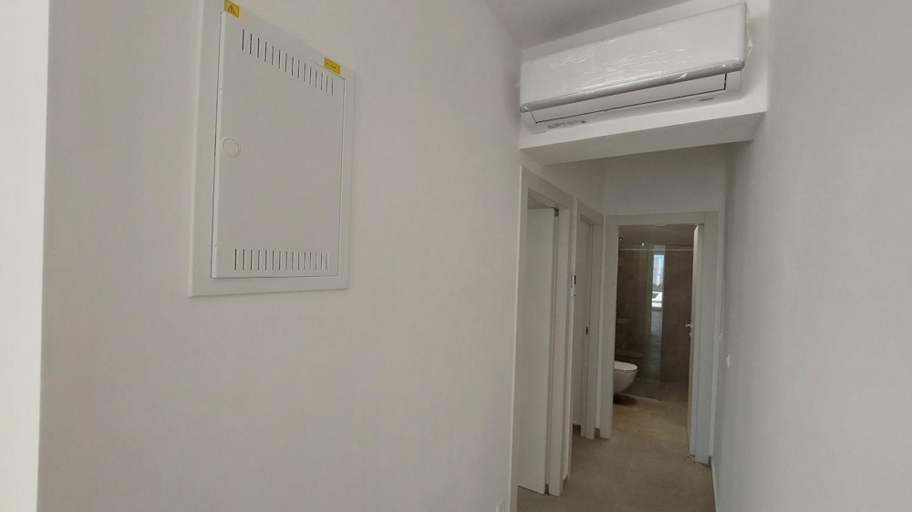 Interiörvy av ett tomt rum med klinkergolv, stora fönster och flera dörrar