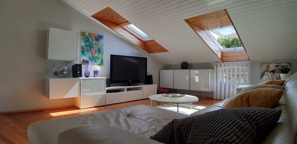 Ett mysigt vardagsrum med takfönster, en stor tv och en bekväm soffgrupp