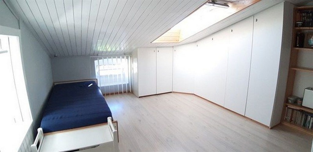 Ett ljust, minimalistiskt sovrum med gott om förvaringsutrymme och takfönster