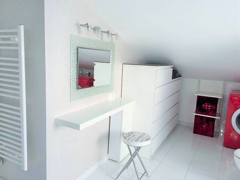 Ett modernt och ljust rum med vita möbler, spegel och tvättmaskin, perfekt som omklädningsrum