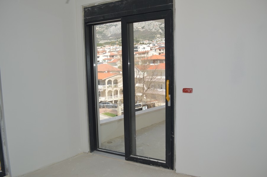 Balkongdörr i en ofärdig lägenhet med utsikt över de omgivande husen och bergen.