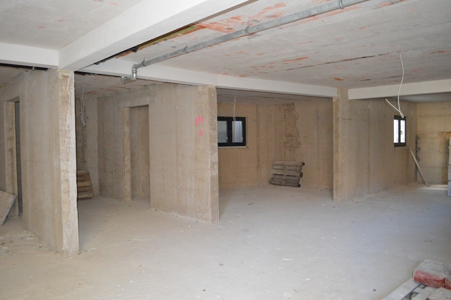 Oavslutat källarrum med betongväggar och golv avsett för parkeringsgarageplatser.