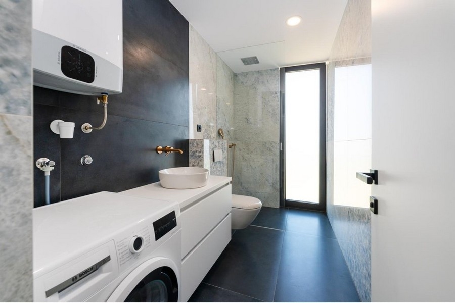 Badrum med tvättmaskin, vit handfat, glasdusch