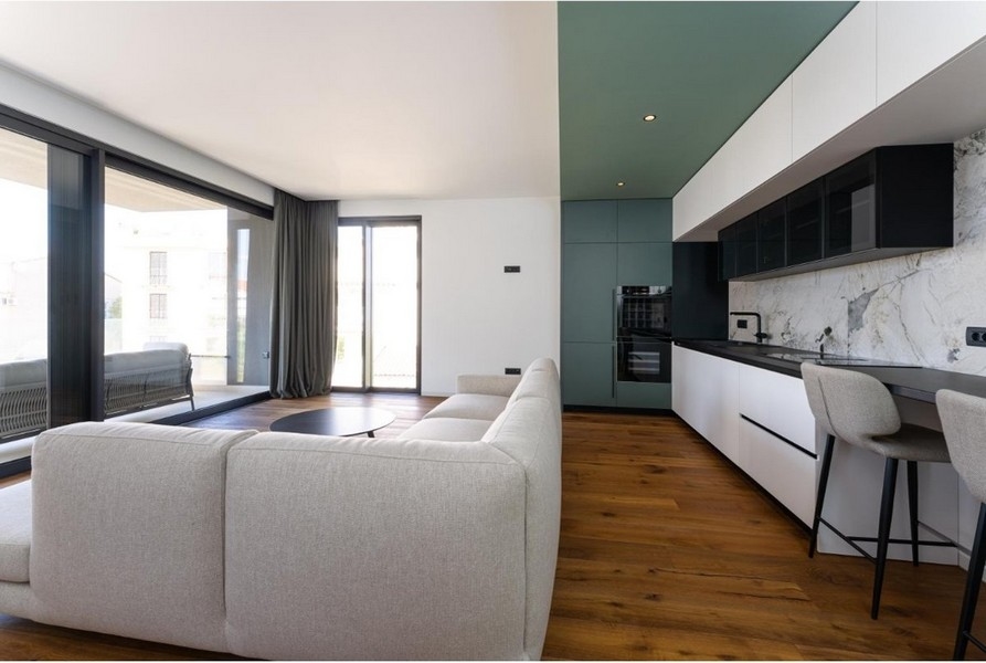 Vardagsrum med hörnsoffa, stora fönster, utgång till balkong