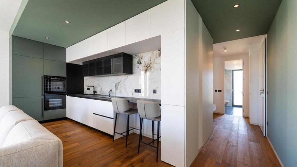 Kök med barstolar, tillgång till hall, trägolv