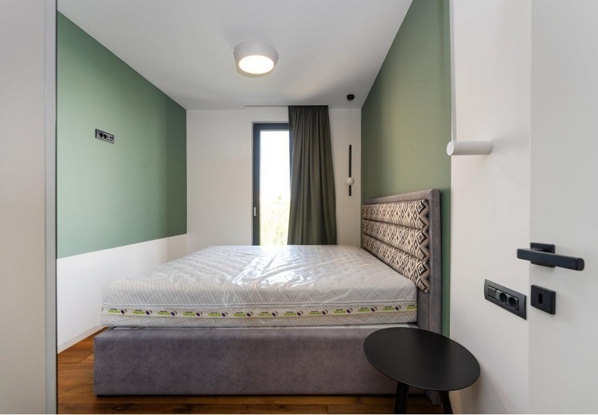 Sovrum med gröna och vita väggar, grå sängstomme