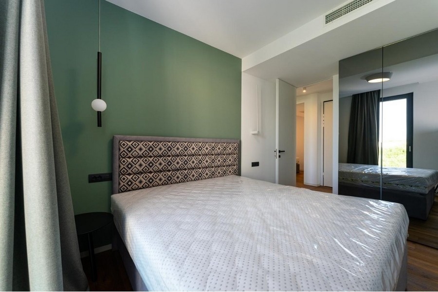 Sovrum med grönmålad vägg och spegelgarderob