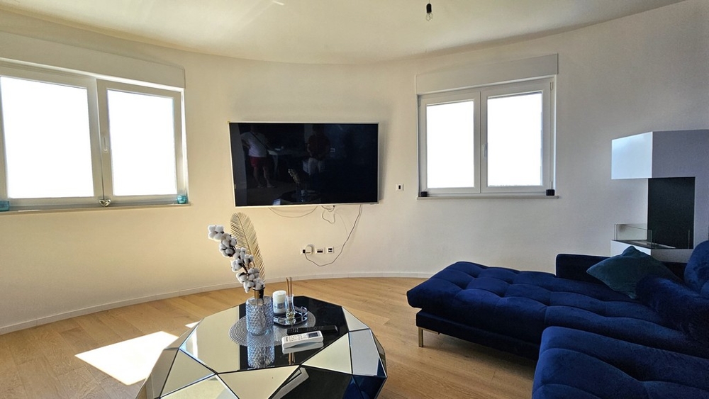 Vardagsrum med stora fönster och en blå soffa