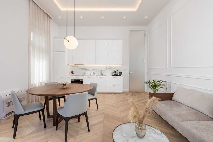 Ljust vardagsrum med matbord, stolar, kök och soffa