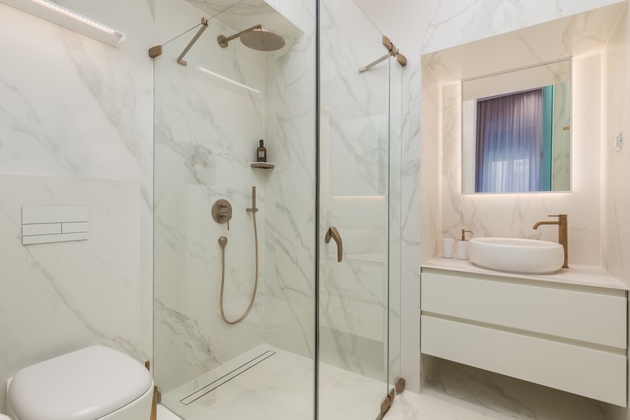 Modernt badrum med glasdusch och marmorkakel