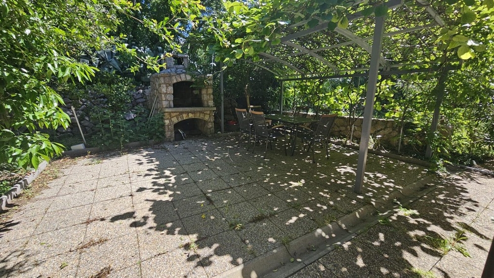 Trädgård med täckt sittgrupp och grill