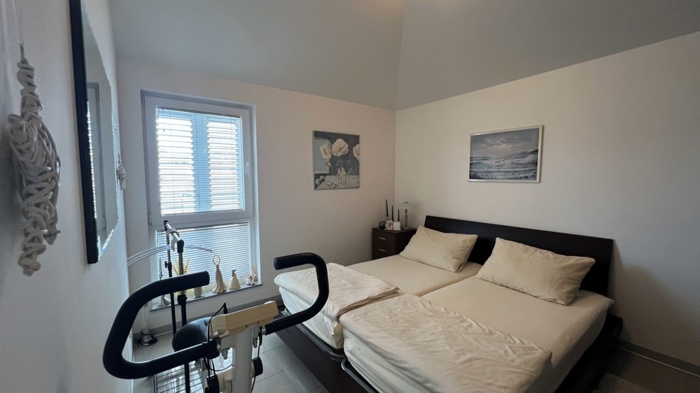 Sovrum med två enkelsängar, motionscykel och minimalistisk inredning.