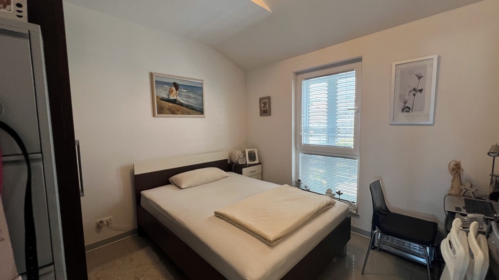 Sovrum med dubbelsäng, enkelt möblerat med fönster mot trädgården.