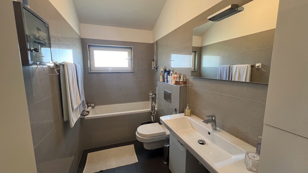 Modernt badrum med badkar, handfat och toalett, enkelt och ljust inrett.