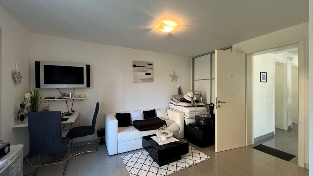 Mysigt vardagsrum i studiolägenheten på bottenvåningen med soffa, skrivbord och TV.