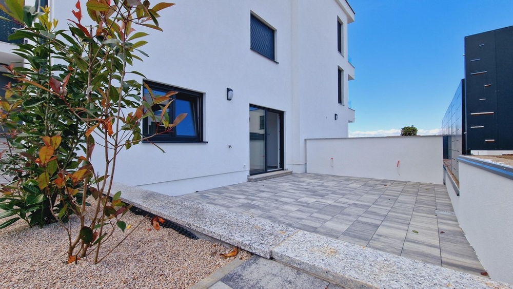 Uteområde i en lägenhet på bottenvåningen med en stenlagd terrass och växter