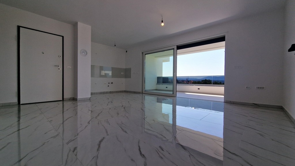 Vardagsrum med utsikt över terrassen och havet, stora skjutdörrar.