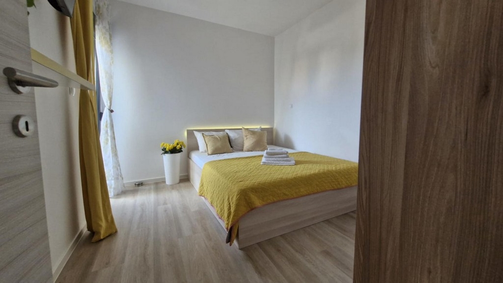 Sovrum med dubbelsäng, gult täcke och dekorationer