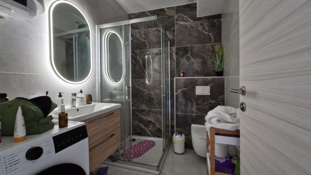 Badrum med dusch, handfat och tvättmaskin