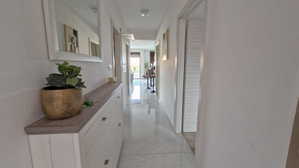 Lägenhetens hall med byrå, spegel och växter